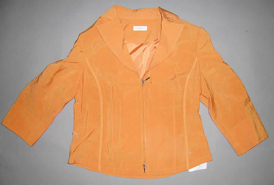 Jacke, sog. Damen-Blusenjacke, Größe 38, siehe Abbildung;
- aus 0,3  mm dicken, einfarbigen Geweben aus lt. Antrag 78% Baumwolle und 22% Nylon
  (synth. Chemiefasern),
- teilweise gefüttert (Rückenteil im Bereich der Schultern),
- über die Taille reichend (Rückenlänge: 56 cm),
- mit einem leicht halsfernen Reverskragen,
- vorn mit einer durchgehenden Öffnung mit einem 2-Wege-Reißverschluss; ohne 
  Überlappung, ohne Merkmale, die auf einen bestimmten Trägerkreis (Männer oder Frauen)
  hinweisen (unisex); entlang der Öffnung mit einem jeweils 7 cm breiten Untertritt,
- mit 3/4-langen Ärmeln,
- mit Schulterpolstern,
- körpernah in Bahnen geschnitten,
- am unteren, leicht gerundeten Rand durch Umschlagen und Festnähen gesäumt,
- kennzeichnet sich aufgrund der Ausstattung (u.a. breiter Untertritt) und des formstabilen
  Schnitts (teilweise gefüttert und in Bahnen gearbeitet) als Jacke, somit keine Hemdbluse 
  der Position 6206,
- wird nicht als äußerstes Kleidungsstück über jeder anderen Kleidung getragen, somit 
  kein Kleidungsstück der Position 6202.