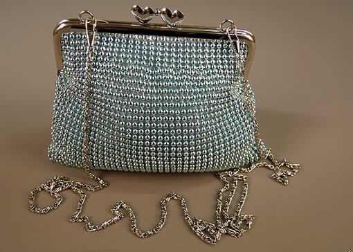 Handtasche (Theatertasche), siehe Foto,
- Handtaschenkörper aus zwei einfarbigen Spinnstofflagen mit einer Zwischenlage aus
  Schaumstoff,
- mit einer Außenseite aus verketteten, silberfarbigen Metallkügelchen, 
- mit den Abmessungen von ca. 18,5 (B) x 14,5 (H) x 2 (T) cm,
- mit einem Metallbügel an der Oberseite, der mit einem Kugelschnappverschluss versehen 
  ist,
- mit einer Metallkette als Tragegurt,
- innen mit einem kleinen Einsteckfach, ansonsten keine weitere Einteilung,
- gefüttert.