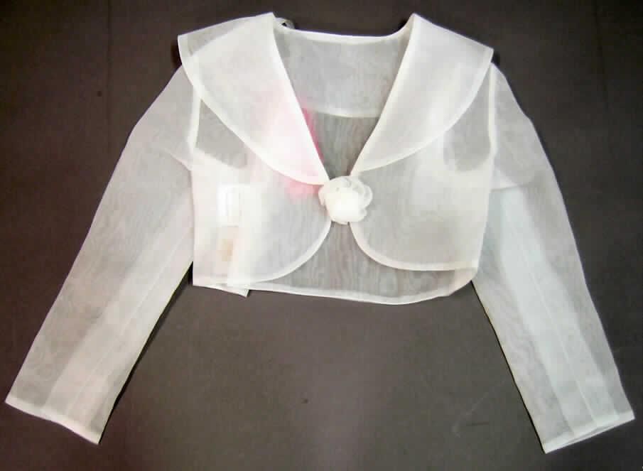 Warenzusammenstellung, bestehend aus einer Jacke und einem anderen konfektionierten Bekleidungszubehör (Brosche), Größe 6-7 (entspricht Größe 116-122), siehe Foto,
- in gemeinsamer Aufmachung für den Einzelverkauf; zur Befriedigung eines speziellen
  Bedarfs zusammengestellt,
- die Jacke bestimmt nach Umfang und Wert den Charakter der Warenzusammenstellung,
- Jacke:
-- aus 0,1 mm dicken, einfarbigen, leicht durchscheinenden Geweben aus laut Etikett
   100% Polyester (synthetische Chemiefasern); 
-- über die Taille reichend (Rückenlänge: 32 cm),
-- vollständig doppellagig gearbeitet, ohne Futter,
-- mit einem V-förmigen halsfernen Halsausschnitt mit einem breiten Umlegekragen,
-- vorn mit einer durchgehenden Öffnung, deren Ränder nicht überlappen, somit ohne
   Merkmale, die auf einen bestimmten Trägerkreis hinweisen (unisex); unterhalb des
   Kragens mit einem innenliegenden Verschluss mit Haken und Öse,
-- mit langen Ärmeln,
-- am unteren, in der vorderen Mitte abgerundeten Rand gesäumt,
-- u.a. aufgrund der Verschlussgestaltung kein Kleidungsstück der Position 6206,
- anderes konfektioniertes Bekleidungszubehör (Brosche):
-- aus denselben Geweben wie die Jacke gearbeitet; in Form einer stilisierten Blüte,
-- auf der Rückseite mit einer Sicherheitsnadel als einfache Vorrichtung zum Befestigen an
   der Kleidung versehen,
-- die Ware kennzeichnet sich nach ihrer Beschaffenheit und ihrem Verwendungszweck als
   individuelles, selbständiges Einzelstück, das die Kleidung als Bekleidungszubehör
   ergänzt,
-- aus Spinnstoffen hergestellt, u.a. somit kein Fantasieschmuck der Position 7117,
-- aufgrund  der Herstellungsweise (durch Zusammennähen) keine künstliche Blume der
   Position 6702, da nicht in einer in der Blumenbinderei üblichen Technik gefertigt.