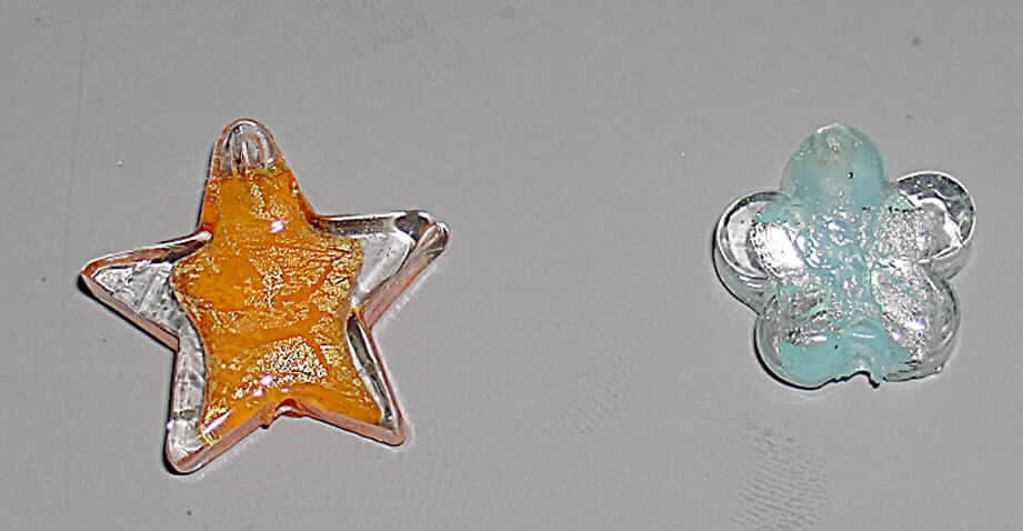 Glasperlen (lt. Antrag Glasperlen "Stern" und "Blume", Art.-Nrn.  21150 und 21151), siehe 
Foto, 
- massive Perlen aus vollständig durchbohrtem Glas, 
- in der Form eines Sterns, mit den Abmessungen von ca. 22 (L) x 5 (H) mm, 
- in der Form einer Blume, mit den Abmessungen von ca 16 (L) x 5 (H) mm, 
- in verschiedenen Farben (16 - 89), 
- nicht geschliffen und mechanisch poliert, da die Perlen weder glatte und scharfkantig abge- 
  grenzte Schleifflächen (Facetten) noch einen geschliffenen Lochrand aufweisen, 
- keine Nachahmung von echten Perlen, Zuchtperlen, Edel-, oder Schmucksteinen, 
- zum Herstellen von z.B. Halsketten u.ä. bestimmt, 
- augenscheinlich nicht handgearbeitet.