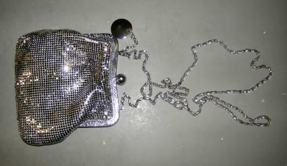 Handtasche (Theatertasche), sog. "Tasche aus Aluminium", siehe Foto,
- Handtaschenkörper aus zwei einfarbigen Spinnstofflagen,
- mit einer Außenseite vollständig aus verketteten, silberfarbigen Metallplättchen, 
- mit den Abmessungen von ca. 16 (B) x 14 (H) x 2 (T) cm,
- mit einem Metallbügel an der Oberseite, der mit einem Kugelschnappverschluss versehen 
  ist,
- mit einer Metallkette als Tragegurt,
- innen mit einem kleinen Einsteckfach, ansonsten keine weitere Einteilung,
- gefüttert.