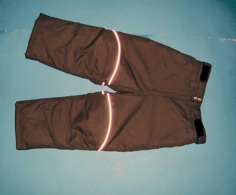 Lange Hose für Mädchen, sog. Robusthose, Artikelnummer: 596-054, Größe 104/110, siehe
beigefügtes Foto,
- aus 0,3 mm dicken, einfarbigen Geweben aus lt. Antrag 100% Polyester (synthetische 
  Chemiefasern); die Gewebe sollen lt. Antrag mit Kunststoff (Polyurethan) bestrichen sein,
  ein Bestreichen mit Kunststoff ist mit bloßem Auge jedoch nicht wahrnehmbar (somit keine
  Meterware der Position 5903 und damit keine Kleidung der Position 6210),
- wattiert und abgesteppt gefüttert,
- in der Taille abschließend, mit einem teilweise elastischen Taillenbund mit seitlich
  angebrachten Klettverschlussriegeln,
- vorn mit einer Öffnung mit Reißverschluss und Patte mit Knopfverschluss im Taillenbund
  von rechts über links (Mädchenkleidung),
- mit zwei seitlich eingesetzten, offenen Taschen,
- mit knöchellangen Hosenbeinen,
- mit reflektierenden Paspeln,
- hinten in Höhe der Oberschenkel mit eingearbeiteten Polstern,
- an den Beinabschlüssen durch Umschlagen und Festnähen gesäumt, zusätzlich mit innen
  eingesetzten, elastischen Abschlüssen (sog. Schneefang).