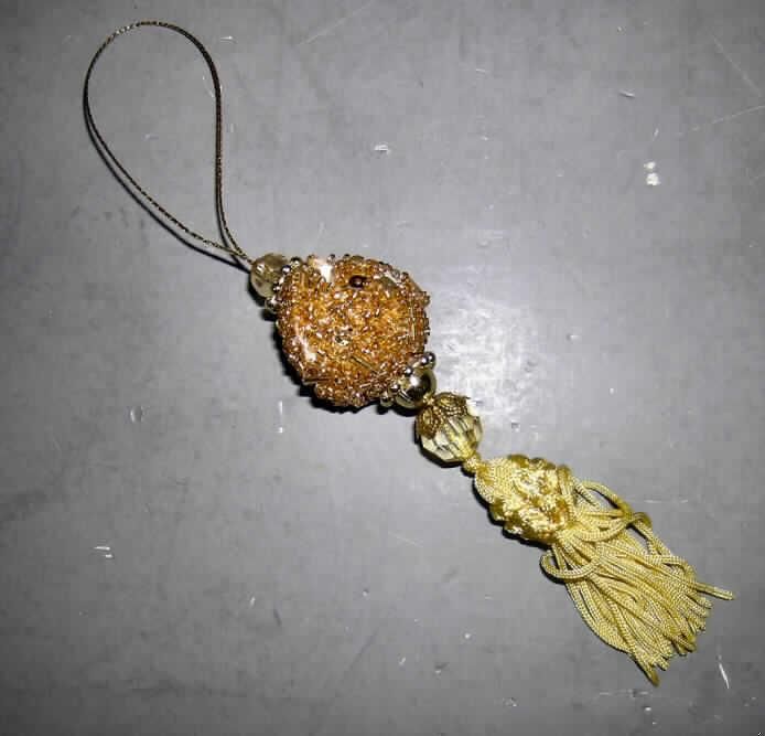 Erzeugnis aus Glaskurzwaren, siehe Foto,
zusammengesetzte Ware (Gesamtlänge ca. 14 cm), bestehend aus
- einem Ei aus Glaskurzwaren mit Aufhängeschlaufe,
-- mit einem Korpus aus Kunststoff (Styropor), der fast vollständig mit Glasperlen und
   Glasröhrchen beklebt ist,
-- da von dem Styroporei keinerlei Zierwirkung ausgeht, bestimmen die Glaskurzwaren im
   Hinblick auf die Funktion (Dekoration) den Charakter dieses Teils der Ware,
- zwei Nachahmungen von Edelsteinen aus Kunststoff, die ober- und unterhalb der Kugel 
  angebracht sind und in der Art eines Facettenschliffs geformt wurden,
- mit einer Troddel aus Spinnstoffen,
die Glaskurzware (Ei) bestimmt vor allem im Hinblick auf den Wert gegenüber dem Kunststoff 
und der Troddel aus Spinnstoff den Charakter der Gesamtware.