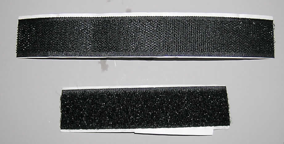 Kautschutiertes Gewebe (Klettverschluss), lt. Antrag "Klettband",
- rechteckig zugeschnitten mit einer Länge (lt. Antrag) von 80 cm und einer Breite (lt. 
  Untersuchung) von 2,6 cm,
- aus einem Hakenband und einem Flauschband aus Samtgeweben aus synthetischen 
  Chemiefasern (lt. Antrag Nylon); (Hakenband: aufgeschnittene Schlinge, Flauschband: nicht
  aufgeschnittene Schlingen), beide auf der Rückseite mit einer mit Klebefolie aus 
  (lt. ergänzenden Antragsangaben: Kautschuk, kein Zellkautschuk) versehen, zusätzlich
  mit einem Schutzpapier abgedeckt,
- mit einer echten Webkante und einer unechten Webkante (heiß geschnitten),
- mit einem Quadratmetergewicht von weniger als 1500 g.