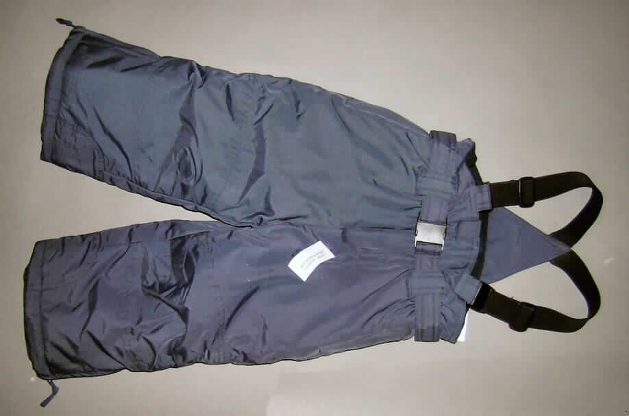 Latzhose für Knaben, sog. lange Hose für Mädchen (Ski-Hose), siehe Foto,
- aus 0,3 mm dicken, einfarbigen Geweben aus laut Antrag 100% synthetischen Chemiefasern;
  die  Gewebe weisen auf der Innenseite einen Glanz auf, ein Bestreichen mit Kunststoff
  ist mit bloßem Auge jedoch nicht wahrnehmbar (keine Meterware der Position 5903;
  somit keine Ware der Position 6210),
- wattiert gefüttert,
- in der Taille abschließend; mit einem elastischen Taillenbund mit einem durch Schlaufen
  geführten Gürtel,
- mit einem Rückenlatz mit angenähten, elastischen, längenverstellbaren Hosenträgern,
- vorn mit einer Öffnung mit Reißverschluss mit einer Patte von links über rechts 
  (Knabenkleidung),
- mit zwei eingesetzten Seitentaschen mit Reißverschluss,
- mit knöchellangen Hosenbeinen mit eingesetzten Schneefängen,
- an den Beinabschlüssen durch Umschlagen und Festnähen gesäumt; mit ca. 12 cm hoch 
  reichenden Reißverschlüssen.
