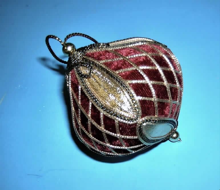 Andere konfektionierte Ware aus Spinnstoffen, sog. Brokat Burgunder-Gold Netz Kreisel, Artikel 279 171,
siehe Foto,
- in Form eines Kreisels mit einer Höhe von ca. 9 cm und einem Umfang von ca. 24 cm,
- mit einem formgebenden Korpus aus Kunststoff, von dem keine Zierwirkung ausgeht,
- mit einem Überzug aus einfarbigen (purpurfarbenen), gerauten Gewirken des Kapitels 60 sowie
  aus kleinen, ovalen Zuschnitten aus Gewirken mit metallisiertem (goldfarbenem) Farbaufstrich
  der Position 5907,
- rautenförmig verziert mit Rundgeflechten,
- durch Kleben konfektioniert,
- am oberen und am unteren Ende jeweils mit einer goldfarbenen Kugel aus Kunststoff verziert,
- mit einer Aufhängeschlaufe aus einem Rundgeflecht,
- im Hinblick auf Umfang und Erscheinungsbild bestimmen die Spinnstoffe den Charakter der Ware; 
  somit keine Ware der Position 3926,
- ohne wesentliche raumbezogene Funktion; somit keine Ware zur Innenausstattung der Position 6304,
- ohne eindeutigen Bezug zum Weihnachtsfest; somit keine Einreihung als Weihnachtsartikel in die
  Position 9505, da die Ware ganzjährig als Dekorationsartikel benutzt werden kann.