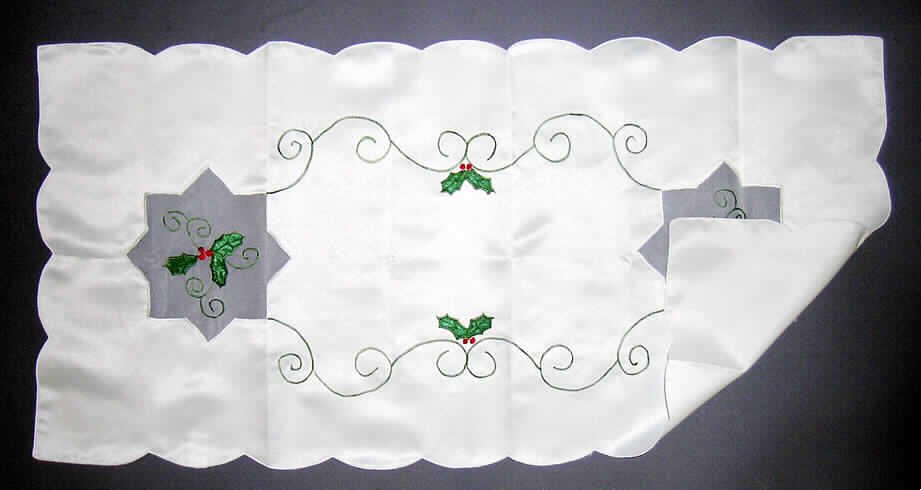 Tischwäsche (Tischdecke), siehe Foto,
- aus 0,5 mm dicken, einfarbigen Geweben aus lt. Antrag 100% Polyester (synthetische Chemiefasern),
- rechteckig, in den Abmessungen: ca. 80 cm x 40 cm,
- an allen Rändern bogig geschnitten und gesäumt (somit konfektioniert),
- mit zwei ca. 16 cm x 16 cm großen, sternförmigen Einsätzen aus transparenten Geweben,
- mit flachen Applikationsstickereien (stilisiertes Laub mit Beeren, Ornamente) verziert,
- kann als sog. Mitteldecke auf die Mitte des Tischs gelegt werden; wird üblicherweise regelmäßig gewaschen 
  und kennzeichnet sich insbesondere aufgrund des Materials und der Ausstattung (keine erhabenen Verzierungen 
  bzw. keine aufgebrachten Verzierungen aus anderen Materialien als Spinnstoff) als Tischwäsche (somit keine
  Ware zur Innenausstattung der Position 6304).