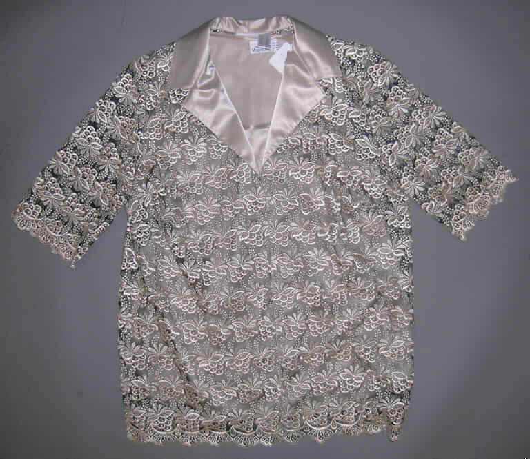 Zweiteilige Zusammenstellung bestehend aus einer Bluse und einer Jacke für Frauen, sog. Blusenset, Art. 72017, Größe 46, siehe Foto
- in gemeinsamer Aufmachung für den Einzelverkauf,
- Bluse:
-- aus 0,3 mm dicken, damit leichten, einfarbigen, glänzenden Geweben aus lt. Antrag
   100 % Polyester (synthetische Chemiefasern),
-- über die Taille reichend (Rückenlänge: 66 cm), mit etwa 8 cm hoch reichenden 
   Seitenschlitzen, 
-- mit einem runden, leicht halsfernen Ausschnitt, 
-- ohne Öffnung und ohne Verschluss,
-- mit Brustabnähern, somit eindeutig als Frauenkleidung erkennbar,
-- ärmellos, 
-- am Halsausschnitt und den Armausschnitten mit einer Randeinfassung gearbeitet,
-- am unteren Rand durch Umschlagen und Festnähen gesäumt.