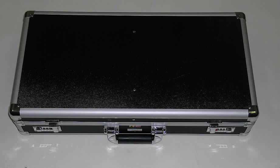 Handkoffer, sog. Instrumenten- oder Waffenkoffer, siehe Fotos, 
- mit einer Außenseite aus schwarz gefärbtem, strukturiertem Aluminium (Ergebnis der 
  augenscheinlichen Untersuchung), welches auf einer Unterkonstruktion aus entsprechend 
  zugeschnittenen Holzfaserplatten aufgeklebt ist, 
- mit einem Rahmen aus Aluminium und Eckverstärkungen aus Stahlblech, 
- mit den Abmessungen von ca. 62 x 36 x 14 cm, 
- mit einem Handtragegriff,
- mit zwei Zahlenschlössern, 
- innen mit Schaumkunststoff ohne spezielle Aussparungen ausgekleidet, 
- zum Transport von Waffen oder Musikinstrumenten vorgesehen.