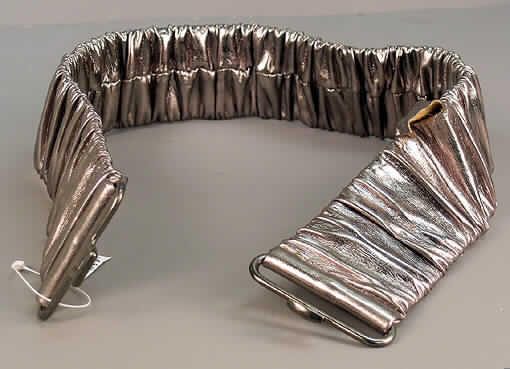 Gürtel (anderes konfektioniertes Bekleidungszubehör), siehe beigefügtes Foto,
- ca. 6 cm breiter Gürtel; mit einer Länge, einschließlich der Schnalle, von ca. 70 cm,
- lt. Untersuchungsergebnis bestehend aus einer Außen- und Innenlage; beide Lagen sind
  lediglich an den Enden des Gürtels miteinander durch Zusammennähen verbunden,
- - Innenlage: aus elastischen, einfarbigen Geweben,
- - Außenlage: aus gerafften, einseitig (Außenseite) mit einem metallisierten Farbaufstrich
    versehenen Zellkunststoff überzogenen, gerauten, dichten Geweben der Position 5903, 
- mit einer Schnalle aus unedlem Metall,
- durch Zusammennähen und Zusammenfügen konfektioniert,
- die Gewebe der Innen- und Außenlage sind im Hinblick auf ihren Umfang und in Bezug auf die
  Verwendung als Gürtel als charakterbestimmend anzusehen.