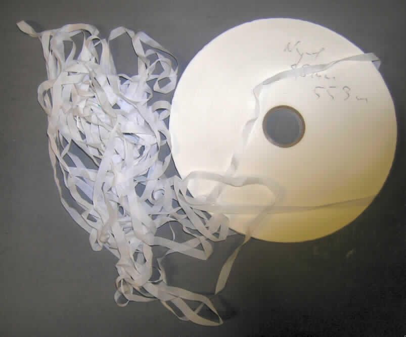 Band, sog. ungetränktes Nylongewebe für Farbbandkassetten, siehe Foto,
- als Meterware,
- auf eine Pappspule (Aufmachung im Sinne der AV 5 b)) aufgewickelt,
- mit einer Breite von 0,9 cm,
- lt. Untersuchungsergebnis 
-- aus weißem Gewebe (kein Samt, Plüsch, Chenille- oder Schlingengewebe) aus synthetischen
   Chemiefasern,
-- keine Elastomergarne oder Kautschukfäden enthaltend,
-- an beiden Längsseiten mit unechten Webkanten gegen das Ausriefeln gesichert 
   (thermisch verfestigt),
- nicht mit Tinte gefärbt oder getränkt oder anders präpariert, um einen Abdruck zu hinterlassen, 
  somit kein den Schreibmaschinenbändern ähnliches Band der Position 9612.