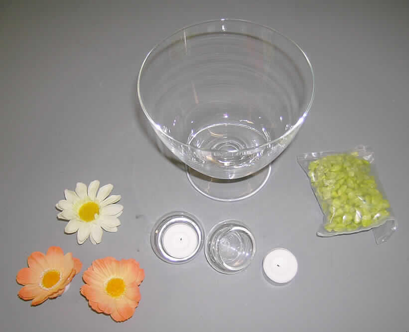Glasware zur Innenausstattung, sog. Glasschale inkl. Dekosteinen, Schwimmblüten,  
Kerzenhaltern und Teelichtern, verpackt in einem Karton, siehe Foto,
Warenzusammenstellung zur Befriedigung eines speziellen Bedarfs (Innendekoration), 
in Aufmachung für den Einzelverkauf, bestehend aus
- einer kegelförmigen Zierschale mit Fuß,
- -  aus augenscheinlich gewöhnlichem, ungefärbtem Glas,
- - mechanisch gefertigt, 
- - mit einem Durchmesser (oben) von ca. 16,5 cm und einer Höhe von ca. 16 cm,
- zwei runden, oben offenen, bauchigen und nach unten hin spitz zulaufenden 
  Zierglasgefäßen ohne Standfläche, sog. Schwimmkerzenhalter,
- - aus augenscheinlich gewöhnlichem Glas, mechanisch gefertigt,
- drei künstlichen Blüten,
- - aus mehreren Teilen (Spinnstoffzuschnitten) durch Ineinanderstecken und Kleben 
    miteinander verbunden, unten mit einem Styroporfuß, sog. Schwimmblüten,
- einer kleinen Kunststofftüte mit zerkleinerten, grün gefärbten Steinen (augenscheinlich 
  Quarzsplitt),
- zwei Teelichtern (Wachs mit Docht in Alunäpfchen eingegossen),
- die Zierschale soll mit Wasser befüllt werden; die gefärbten Steine, die Schwimmblüten 
  und die Schwimmkerzenhalter mit Teelichtern werden eingelegt, 
- im Hinblick auf den Umfang und den Verwendungszweck bestimmt die Zierschale aus 
  Glas gegenüber den gefärbten Steinen, den Schwimmblüten, den Schwimmkerzenhaltern 
  aus Glas und den Teelichtern (Verbrauchsmaterial) den wesentlichen Charakter der Waren-
  zusammenstellung, 
- die Waren sind gemeinsam in einer handelsüblichen Verkaufsumschließung verpackt,
- keine Zuweisung zu Pos. 9405 als nichtelektrischer Beleuchtungskörper, weil es sich nicht
  um einen herkömmlichen Beleuchtungskörper handelt und die Schwimmkerzenhalter nicht
  passgenau zur Aufnahme der Teelichte sind.