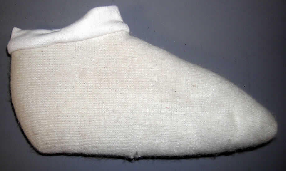 Andere Strumpfware, sog. Pantoffeln oder andere Hausschuhe; Style Wooly Warmers, in
Erwachsenengröße, siehe beigefügtes Foto,
- aus ca. 1 cm dicken Gewirken (Hochflorerzeugnis) mit einem Grund aus Chemiefasern und
  einer Floroberfläche aus lt. ergänzenden Antragsangaben 100% Wolle,
- die Floroberfläche bildet die Innenseite der Strumpfware, 
- am oberen Rand mit einem angesetzten, ca. 3 cm breiten Streifen aus glatten Gewirken,
- durch Zusammennähen konfektioniert,
- vollständig den Fuß umschließend und bis zum Knöchel reichend,
- ohne angebrachte Laufsohle, somit keine Schuhe des Kapitels 64.