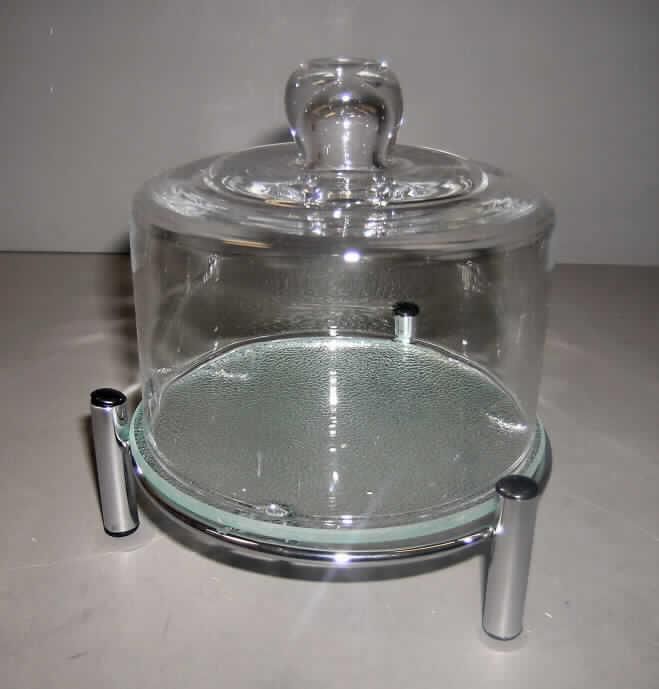 Warenzusammenstellung, bestehend aus einer zweiteiligen Glasware zur 
Verwendung bei Tisch oder in der Küche und einem Haushaltsartikel (Metallständer) aus
unedlem Metall, sog. "Käse-/Butterglocke, Glas/Chrom, Artikel: 26273", siehe Foto,
in Aufmachung für den Einzelverkauf, zur Befriedigung eines speziellen Bedarfs
zusammengestellt, bestehend aus 
- einer Glasware zur Verwendung bei Tisch oder in der Küche (Käseglocke), in Form einer
  zylindrigen Glocke mit Griff, die auf einen Glasteller aufgesetzt wird,
- -  mit einer Höhe von (ohne Griff) ca. 9 cm und einem Durchmesser von ca. 13,5 cm,
- einem passgenauen Metallständer aus verchromtem, nichtrostendem Stahl zur 
  Aufbewahrung der Käseglocke, 
- die Glasware zur Verwendung bei Tisch oder in der Küche bestimmt insbesondere im Hin- 
  blick auf ihre Bedeutung in Bezug auf die Verwendung den Charakter der Waren- 
  zusammenstellung,
- verpackt in einem handelsüblichen Karton.