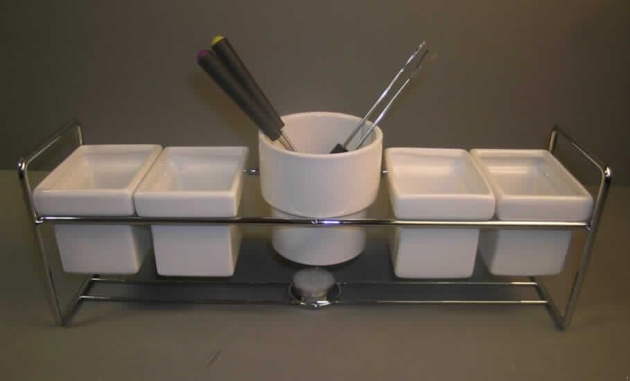Warenzusammenstellung, Schokoladenfondue bestehend aus fünf keramischen Haushaltsartikeln, einem Teelicht, vier Fonduegabeln und einem Metallgestell, sog. "Tisch-/Fondue-Set, Art. Nr.: 26363", siehe Foto, 
in Aufmachung für den Einzelverkauf, zur Befriedigung eines gemeinsamen Bedarfs (Zubereiten von Schokofondue), bestehend aus
- fünf keramischen Haushaltsartikeln für den Tisch- oder Küchengebrauch, 
- - ein zylindriges, weiß glasiertes Gefäß zum Schmelzen der Schokolade,
- - - mit einer Höhe von ca. 9 cm und einem Durchmesser (oben) von ca. 9 cm,
- - vier rechteckige Schalen zum Anrichten der Früchte,
- - - mit den Abmessungen von ca. 9 x 7 x 7 cm,
- - keramische Erzeugnisse, nach der Formgebung gebrannt, tonmineralhaltiges Material,
- - nach dem Ergebnis der augenscheinlichen Untersuchung handelt es sich um Steingut,
    (hellcremefarbener Scherben, an der Zunge haftend),
- einem Teelicht,
- vier Fonduegabeln, 
- - mit einem arbeitenden Teil aus unedlem Metall,
- einem Gestell aus unedlem Metall zum Einhängen der Schalen und zum Einstellen 
  des Teelichts,
- - mit den Abmessungen von ca. 41 x 10 x 14 cm,
- die keramischen Haushaltsartikel aus Steingut bestimmen nach dem Umfang und
  deren Bedeutung in Bezug auf die Verwendung den wesentlichen Charakter der
  Warenzusammenstellung.