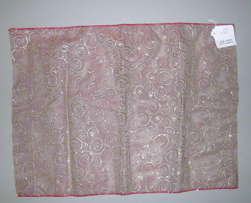Andere konfektionierte Spinnstoffware, sog. Dekostoff aus Organza, Art. 60385, siehe Abbildung; 
- aus 0,4 mm dicken, einfarbigen, durchscheinenden, musterbildend bedruckten (goldene 
  Ornamente und Sterne) Geweben aus lt. Antrag synth. Chemiefasern,
- soll in den Abmessungen: 10 m x 0,40 m auf einer Papprolle aufgerollt eingeführt werden
  und wird durch einen Probenabschnitt (ca. 40 cm X 55 cm) veranschaulicht,
- nicht handgearbeitet,
- an den Längsseiten durch Überwendlichnähte gesäumt (damit konfektioniert),
- stellt sich aufgrund der Abmessungen und der neutralen Form weder als Tischwäsche
  der Position 6302, noch als Gardine der Position 6303 oder als eine andere Ware dar, die 
  ausschließlich oder hauptsächlich zur Innenausstattung verwendet wird (somit auch
  keine Ware der Position 6304).
