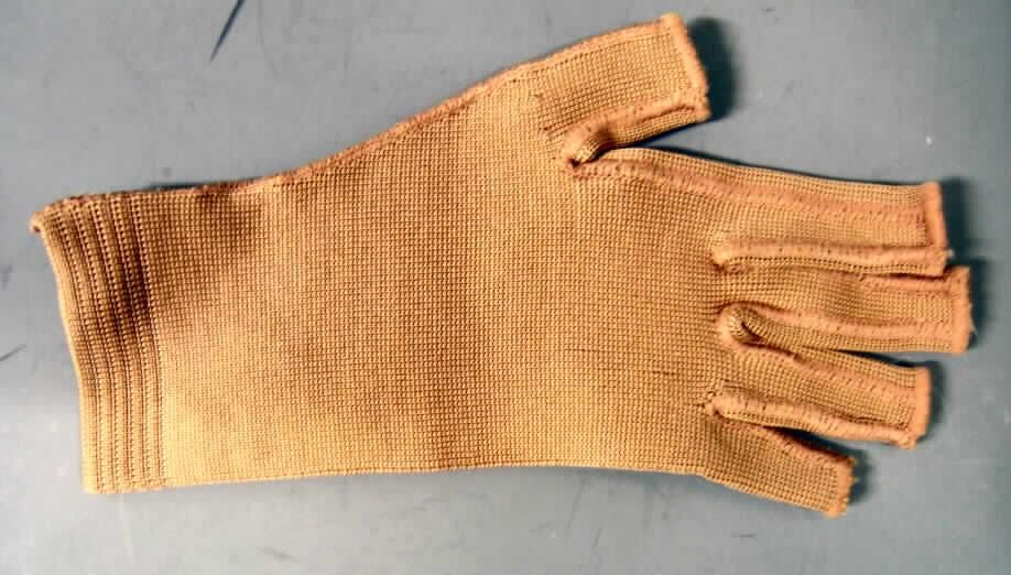 Handschuh, in Erwachsenengröße, siehe Foto,
- als Fünffingerhandschuh ohne Fingerkuppen gearbeitet,
- aus 1,7 mm dicken, glatten, elastischen Gewirken aus laut Antrag 80 % Polyamid und 20% 
  Elastan (synthetische Chemiefasern),
- laut Antrag u.a. zur Kompression, um eine Bildung von Ödemen zu verhindern,
- eine Stützfunktion ergibt sich ausschließlich aus der Elastizität der Spinnstoffe, daher 
  keine Einreihung als "orthopädische Vorrichtung" der Position 9021,
- wird nicht vom Warenkreis der Position 6115 umfasst.