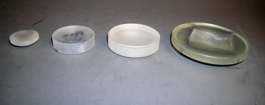 Rohlinge von optischen Elementen, sog. Presslinge aus Rohglas, siehe Foto,
- nach der wissenschaftlichen Untersuchung aus optischem Glas,
- in Form von Zylindern mit angepressten Radien (Kurven) oder mit unendlichen Radien 
  (plan), 
- vier vorgelegte Warenmuster: runde, dicke, kleine, farblose, matt-trübe Glasscheibe mit 
  einem Durchmesser von 4,2 cm und einer Dicke von 1,2 cm; runde, kleine, farblose, 
  transparente, matt-trübe Glas-Linse (bikonvexe Sammellinse) mit einem Durchmesser von 
  2,8 cm und einer Dicke von 1,24 cm; runde, farblose, transparente, matt-trübe Glas-Linse 
  (plankonvexe Zerstreuungslinse) mit einem Durchmesser von 5,2 cm und einer Dicke von 
  1,37 cm; runde, farblose, leicht grünstichige, transparente, teils matt-trübe, teils
  glatt-klare Glaslinse (konkavkonvexe Sammellinse) mit einem Durchmesser von 7,8 cm und 
  einer Dicke von 1,5 cm,
- durch Erhitzen mechanisch in Form gepresst,
- nicht weiter bearbeitet,
- nicht optisch bearbeitet (nicht geschliffen oder poliert),
- nicht für Uhren oder Brillen bestimmt,
- zur Herstellung von optischen Elementen (z. B. Linsen) der optischen Industrie.
