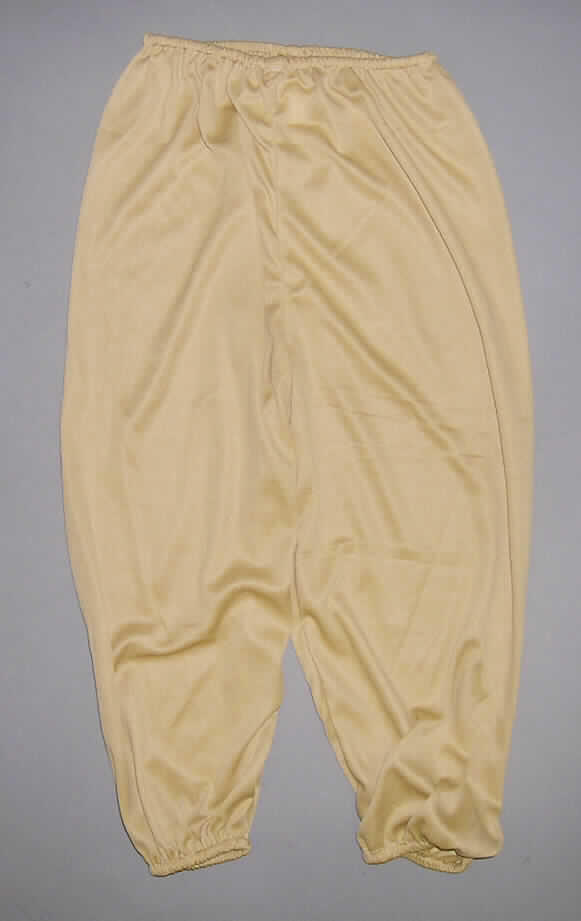Fünfteilige Zusammenstellung, bestehend aus einer Hemdbluse, einer langen Hose, Bekleidungszubehör aus Zellkunststoff (Gürtel und Stulpen) und einer Kopfbedeckung (Hut), sog. Robin Hood (Art. 87124), Größe 110 bis 146, siehe Fotos,
- gemeinsam für den Einzelverkauf aufgemacht und zur Befriedigung eines speziellen Bedarfs zusammengestellt,
- gehört als Maskenkostüm aus Spinnstoffen nicht zum Warenkreis der Karnevalsartikel der Position 9505,
- getrennte Einreihung aller Bestandteile, u. a. weil die Kleidungsstücke nicht zusammen in eine Position eingereiht 
  werden können,
- lange Hose:
-- aus 0,5 mm dicken, einfarbigen Gewirken aus lt. Antrag 100% synthetischen Chemiefasern,
-- in der Taille abschließend mit einem elastischen Zug,
-- ohne Öffnung und ohne Verschluss; ohne Merkmale, die auf den Trägerkreis hinweisen (unisex),
-- mit knöchellangen Hosenbeinen (Seitenlänge: 62 cm),
-- an den Beinabschlüssen durch einen elastischen Zug verengt.