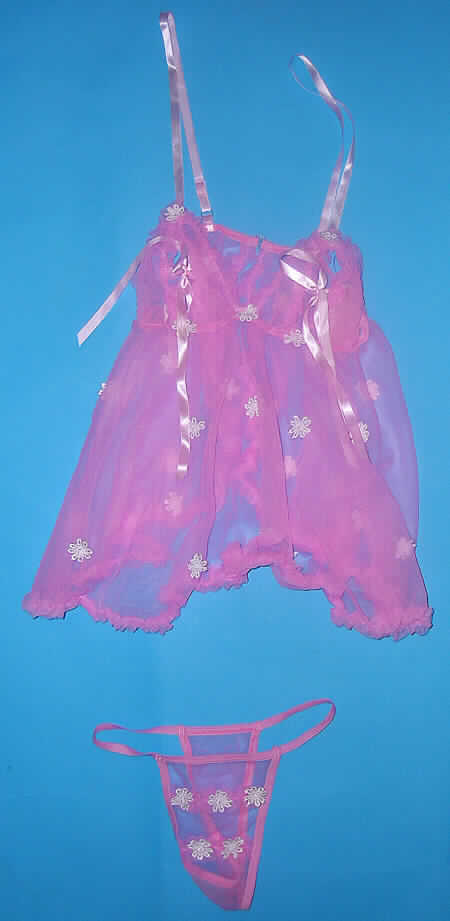 Schlafanzug bestehend aus einem sehr kurzen Nachthemd und einem slipähnlichen Kleidungsstück (Baby Doll), sog. Baby Doll, Hersteller-Artikelnummer 464, Größe S, siehe beigefügtes Foto,
- gemeinsam für den Einzelverkauf aufgemacht,
- aus 0,3 mm dicken, durchscheinenden, einfarbigen Gewirken aus lt. Antrag 90% Polyamid
  und 10% Spandex (beides Chemiefasern); das fertige Kleidungsstück bzw. die Zuschnitte 
  sind mit kleinen, kontrastfarbenen Blüten (Applikationsstickerei) verziert (Meterware: keine 
  Stickerei der Position 5810),    
- aufgrund des Schnitts eindeutig als Frauenkleidung erkennbar,
- Oberteil: über die Taille reichend (Rückenlänge: ca. 62 cm); mit verstellbaren
  Spaghettiträgern aus Geweben; mit ausgearbeiteten Büstenteilen; im Bereich der Büste
  weitgehend offen und mit zu Schleifen gebundenen, gewebten Bändern versehen; im
  Rückenteil durchgehend offen und mit Hakenverschluss am oberen Rand; an den Rändern 
  gerüscht und gesäumt; zum unteren Rand hin weit geschnitten,
- slipähnliches Kleidungsstück; in Form eines Tangaslips gearbeitet; mit einem elastischen
  Band aus Gewirken im Taillenabschluss; mit sehr hohen Beinausschnitten, die mit 
  elastischen Bändern gearbeitet sind; ohne Öffnung und ohne Verschluss; vorn mit zwei 
  schmalen, gerüschten Gewirkestreifen und aufgenähten Blüten verziert; im Schritt nicht 
  doppelt gearbeitet und ohne Hygieneeinlage, kennzeichnet sich jedoch aufgrund der 
  Ausstattung und des Verwendungszwecks als slipähnliches Kleidungsstück,
- insbesondere nach Schnitt, Material, Farbe und Ausstattung erkennbar dazu bestimmt,
  ausschließlich oder im Wesentlichen als Nachtkleidung (sog. Baby Doll) im Bett getragen
  zu werden.