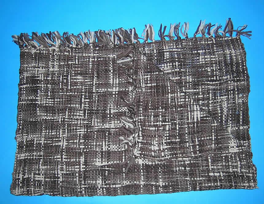 Decke (Kat. 7985), siehe Foto,
- aus 5,0 mm dicken, buntgewebten Geweben aus lt. Antrag 100% Wolle,
- rechteckig, in den Abmessungen 169 cm x 115 cm,
- an den Längsseiten mit echter Webkante; an den beiden kurzen Seiten durch geknüpfte, 
  11 cm lange Fransen gesäumt (somit konfektioniert), nicht handgearbeitet,
- ohne elektrische Heizvorrichtung,
- kennzeichnet sich nach Material, Ausstattung und Abmessung als Decke der Position 
  6301 und nicht als Bettüberwurf (Gegenstand zur Innenausstattung) der Position 6304.