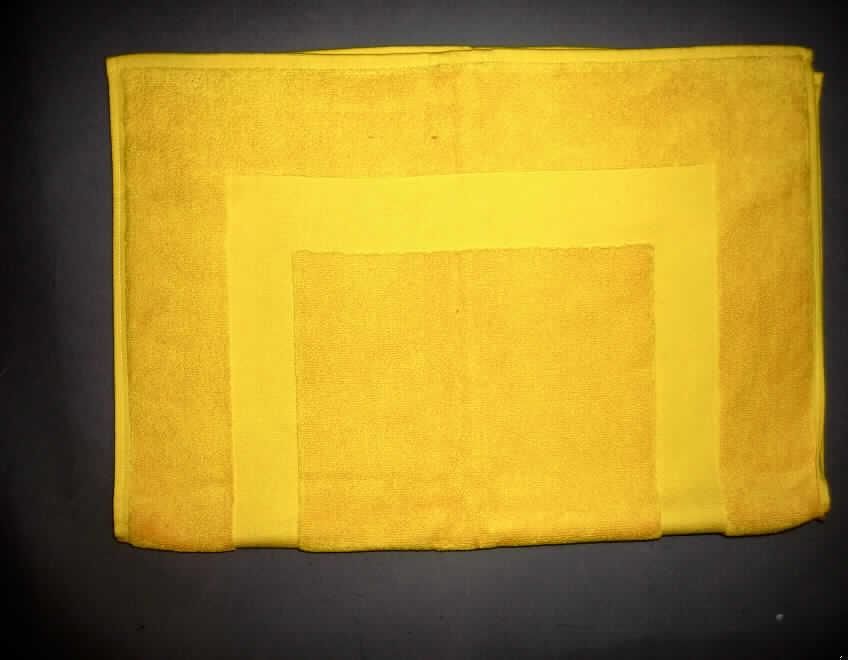 Fußbodenbelag, sog. Badematte, Artikel 9002, siehe Foto
- rechteckig in den Abmessungen: 58 x 77 cm,
- Dicke: ca. 4 mm,
- aus einfarbigen Schlingengeweben (Frottiergeweben) aus laut Antrag 100% Baumwolle, 
  auf der einen Seite sind die Schlingen Muster bildend entfernt worden,
- an den Rändern durch Umschlagen und Festnähen gesäumt (= konfektioniert),
- aufgrund des Verwendungszwecks (Vorleger für Badewanne und Dusche) und der Materialbeschaffenheit 
  nicht zur Verwendung als Wäsche zur Körperpflege (Position 6302) bestimmt und auch keine Ware zur 
  Innenausstattung der Position 6304.