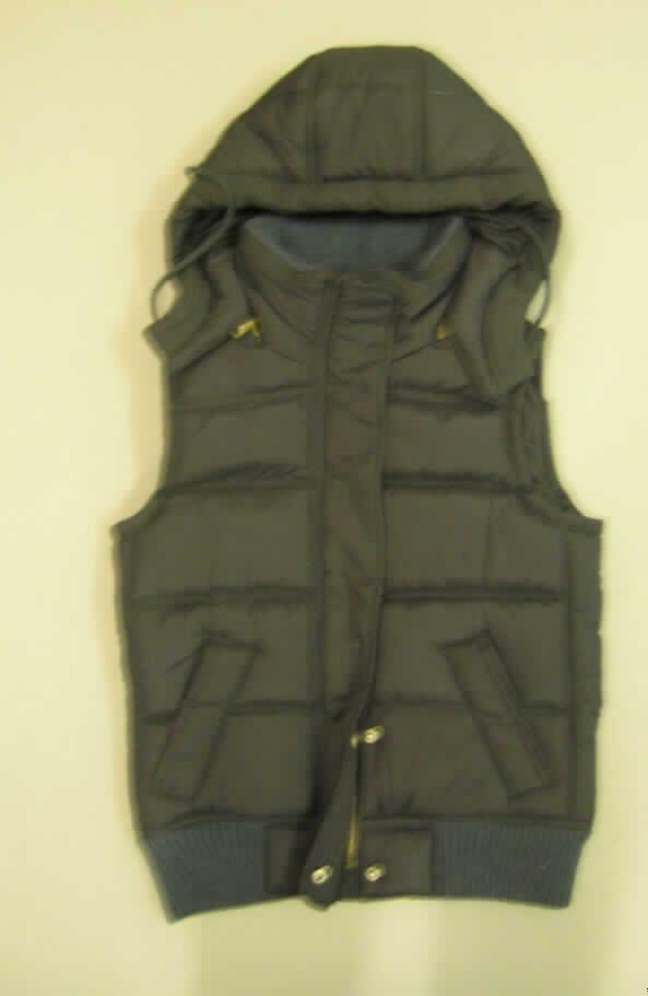 Weste für Frauen, sog. Colorado Vest, Größe S
- aus einem zweilagigen, durch Steppen abgeteilten Verbunderzeugnis der Position 
  5811, mit einer charakterbestimmenden Außenlage aus 0,1 mm dicken, einfarbigen  
  Geweben aus laut Antrag 100 % Polyester (synthetische Chemiefasern) und einer 
  Innenlage aus Wattierungsstoff,
- durchgehend mit einem dünnen Futterstoff aus Gewebe gefüttert,
- über die Taille reichend (Rückenlänge: 69 cm),
- mit einem Stehkragen, innen mit einem Besatz aus einem gerippten Gewirke, mit einer 
  mittels Reißverschluss abtrennbaren Kapuze, 
- vorn mit einer durchgehenden Öffnung, mit einem bis in die Kragenspitzen reichenden
  Reißverschluss, verdeckt von einer Patte mit Druckknöpfen von rechts auf links 
  (Frauenkleidung),
- ärmellos, an den Armöffnungen durch Umschlagen und Festnähen gesäumt,
- mit eingesetzten Taschen unterhalb der Taille,
- am unteren Rand mit einem verengenden, gerippt gewirkten Bund.