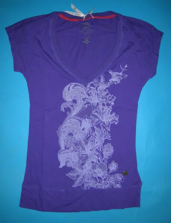 Modisches Unterhemd, sog. T-Shirt, Größe  36/S, siehe Foto,
- aus 0,7 mm dicken (leichten), einfarbigen Gewirken aus laut Antrag 100% Baumwolle,
- über die Taille reichend (Rückenlänge: 67 cm),
- vorn mit einem V-förmigen, halsfernen, jedoch nicht sehr tiefen Halsausschnitt mit gerippter
  Randeinfassung (somit u.a. kein Kleidungsstück der Position 6106),
- ohne Öffnung und ohne Verschluss,
- mit sehr kurzen Ärmeln,
- modisch gestaltet, auf der Vorderseite großflächig bedruckt,
- wird unmittelbar auf der Haut getragen,
- am unteren Rand mit einem angesetzten, nicht verengenden Bund.