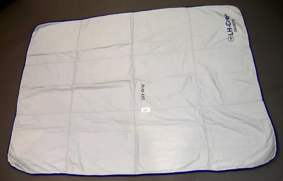 Decke, sog. Steppdecke,
- rechteckig; laut Antrag in den Abmessungen von 130 cm x 200 cm,
- aus einem dreilagigen, ca. 2,5 mm dicken, durch Nähen miteinander verbundenen
  Flächenerzeugnis aus Geweben; laut Antrag bestehen die Außenlagen aus 
  100% Baumwolle; laut Untersuchungsergebnis mit einer 1,1 mm dicken Zwischenlage
  aus Geweben (somit keine gepolsterte Ware im Sinne der Position 9404),
- an den anderen Rändern mit Bändern aus Geweben eingefasst (somit konfektioniert),
- nicht handgearbeitet; ohne elektrische Heizvorrichtung,
- kennzeichnet sich nach Material und Ausstattung als Decke.