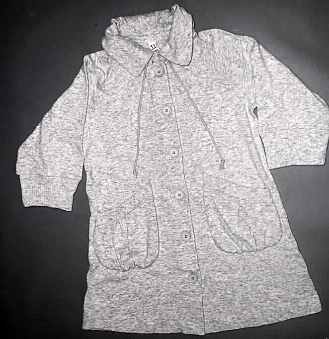 Strickjacke für Frauen, sog. Strickjacke für Damen, Größe 38, siehe Foto
- aus 1,6 mm dicken, melierten, leicht gerauten Gewirken aus lt. Antrag 45 % Wolle.
  44 % Baumwolle und 11 % Polyamid (synthetische Chemiefasern),
- über den Schritt, aber nicht über die Mitte der Oberschenkel hinausreichend
  (Rückenlänge: 84 cm), 
- mit einem halsnahen Umlegekragen, am Kragenansatz
  mit einem Tunnelzug,
- vorn mit einer durchgehenden Öffnung, mit Knopfverschluss von rechts über links 
  (Frauenkleidung); der unterste Knopf befindet sich 15 cm oberhalb des unteren 
  Randes (damit nicht schrittbedeckend geknöpft, somit u.a. kein Kleid der Position 6104),
- mit 3/4-langen Ärmeln, an den Ärmelenden mit einem breiten Bündchen,
- vorn mit zwei eingesetzten Taschen unterhalb der Taille (somit keine Hemdbluse der 
  Position 6106),
- ungefüttert, nicht in Bahnen gearbeitet, weist keine Formfestigkeit auf (u. a. auch deshalb 
  keine Jacke der Position 6104),
- am unteren Rand durch Umschlagen und Festnähen gesäumt.