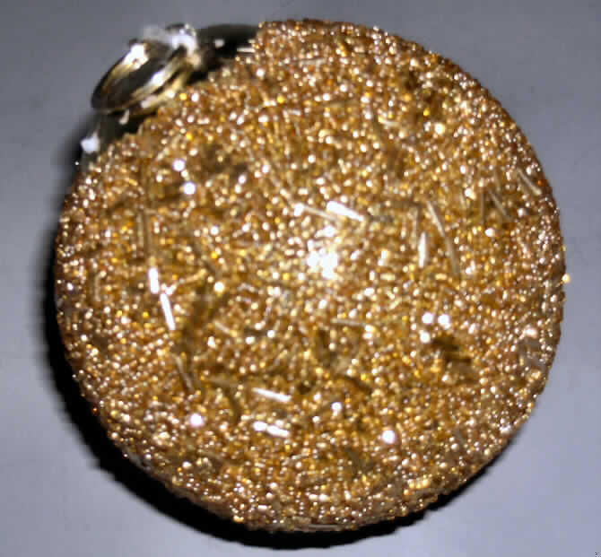 Erzeugnis aus Glaskurzwaren, sog. "Glaskugel Pompadour d 10 cm", siehe Foto,
- in Form einer Kugel mit Aufhängeschlaufe und einem Durchmesser von ca. 10 cm,
- mit einem formgebenden Korpus aus klarem Glas, von dem keine Zierwirkung ausgeht,
- mit goldfarbenen, durchbohrten Glasperlen mit einem Durchmesser von jeweils ca. 2 mm
  in Form von Körnern mit einer Länge von ca. 2 mm sowie in Form von Röhrchen mit einer 
  Länge von ca. 7 mm beklebt,
- am oberen Ende mit einem aufgeklebten Krönchen aus Metall mit einer dadurch 
  gezogenen Aufhängeschlaufe mit einer Länge von ca. 9 cm versehen,
- im Hinblick auf den Umfang und das äußere Erscheinungsbild sind die Glaskurzwaren 
  als charakterbestimmend anzusehen,
- keine Einreihung als Weihnachtsartikel in die Position 9505, da aufgrund der ganzjährigen
  Verwendbarkeit kein erkennbarer Bezug zur Advents- bzw. Weihnachtszeit gegeben ist.