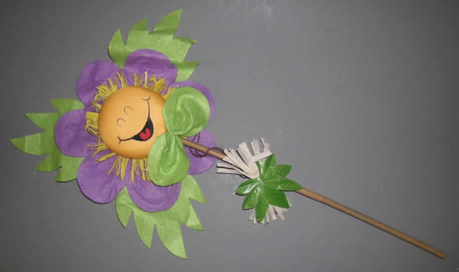 Künstliche Blume (lt. Antrag: "Blumenstecker Lachende Blume",siehe Foto)
- in Form einer stilisierten Blume (Höhe ca. 55 cm),
- mit einem Stengel aus einem Stab aus (lt. Antrag) Bambus mit einem Durchmesser 
  von ca. 7 mm, 
- am oberen Ende des Stengels ist eine Blüte (Durchmesser: ca. 20 cm) befestigt, 
  im Wesentlichen bestehend aus:
  -- einem Fruchtknoten in Form einer Styroporscheibe (ohne Zierwirkung) , die vollständig mit 
     einem Gewebe aus Spinnstoff überzogen wurde,
  -- Staubgefäßen aus buntgefärbtem Stroh und Blütenblättern aus Filz aus Spinnstoff,
  -- am untern Ende mit Bastfasern und einem Spinnstoffblatt verziert,
- alle Teile wurden durch Kleben zusammengefügt,
- auf den Fruchtknoten ist ein Gesicht aufgedruckt, 
- zur Verwendung als Dekorationsgegenstand