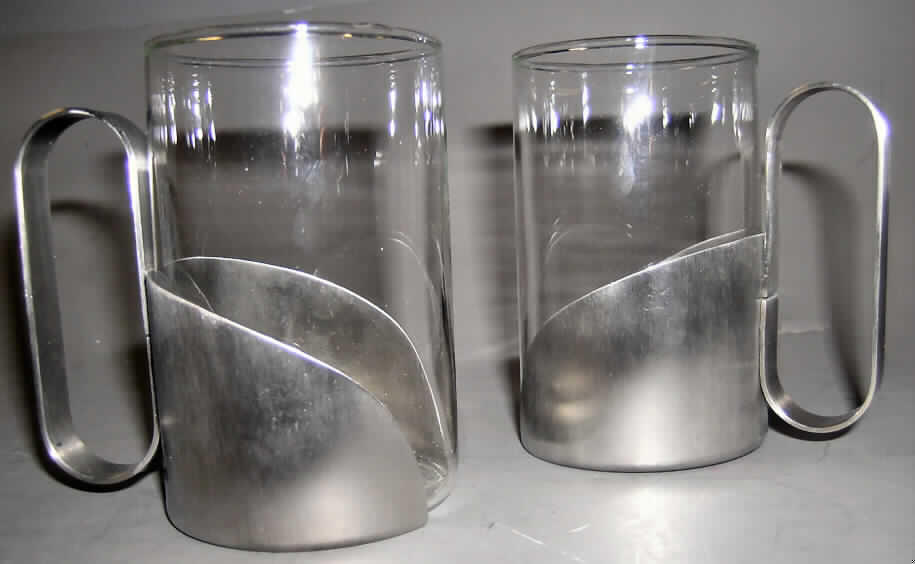 Glaswaren zur Verwendung bei Tisch, sog. "Teegläser mit Edelstahlhalter, 2fach", 
siehe Foto,
- zusammengesetzte Ware, bestehend aus
-- einem Teeglas aus gewöhnlichem Glas,
--- mechanisch gefertigt (mechanische Glasentnahme),
--- mit einem Durchmesser von ca. 6 cm (oberer Rand),
--- mit einer Höhe von ca. 10 cm,
--- zur Verwendung bei Tisch,
--- nicht geschliffen oder anders bearbeitet,
-- einer Halterung aus nichtrostendem Stahl (lt. Antrag Edelstahl),
--- in Form eines das Teeglas teilweise umschließenden Halbmondes,
--- mit einem angearbeiteten Griff,
--- passgenau auf den unteren Rand der Tasse aufgesteckt,
- das Teeglas bestimmt insbesondere aufgrund seiner Bedeutung in Bezug auf die 
  Verwendung den Charakter der zusammengesetzten Ware,
- in einer handelsüblichen Verkaufsumschließung verpackt (Karton).