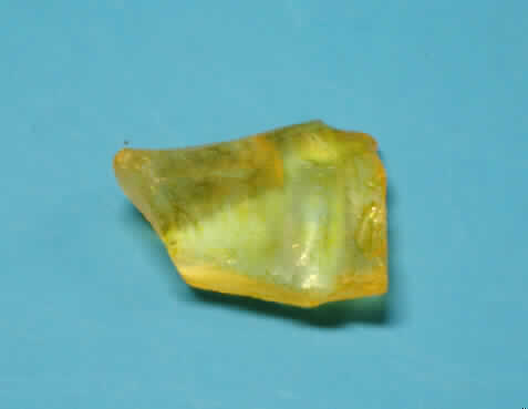 Bruchglas (lt. Antrag Glasstein, Bruch, Art.-Nr. 7615), siehe Foto, 
- mit unregelmäßigen Bruckkanten (keine scharfen Kanten), 
- unregelmäßige Dicke und Form, 
- farbig überzogen (gelb), 
- mit den Abmessungen von ca.  2,5 (L) x 2 (B) cm, 
- keine Nachahmung von Edelsteinen oder Schmucksteinen, da sie nicht unmittelbar geformt 
  sind und keine ausgeschnittenen Stücke aus Glasblöcken darstellen.