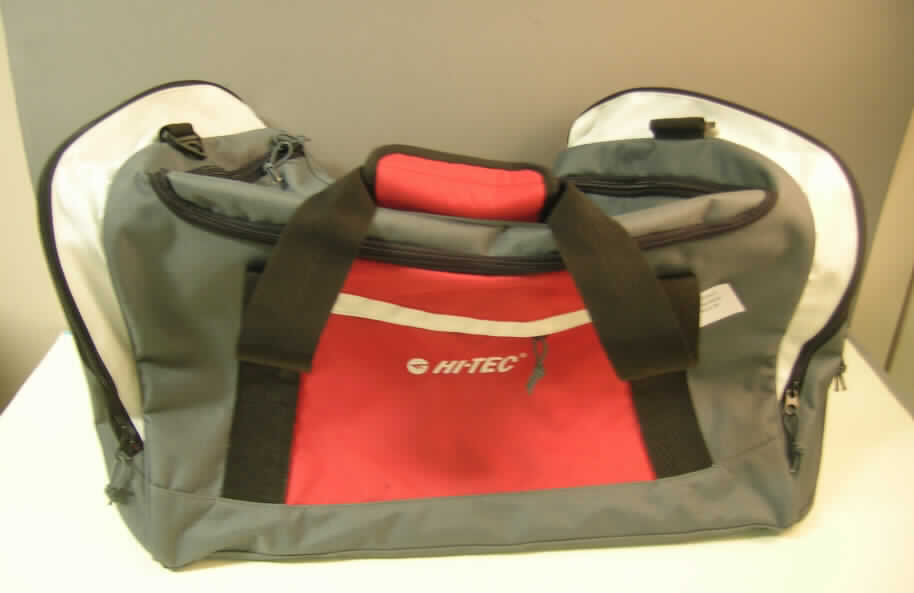 Reisetasche, sog. HI-TEC Sporttasche,
- mit einer Außenseite aus Spinnstoffen auf einer Unterlage aus Kunststofffolie, 
- mit zwei Handtragegriffen, 
- mit einem abnehmbaren, verstellbaren Schultertragegurt, 
- mit fünf runden Stellfüßen,
- mit einem eingesetzten Vorfach mit Reißverschluss,
- an beiden Schmalseiten mit jeweils einem aufgesetzten Reißverschlussfach,
- mit einem an einer Schmalseite aufgenähten Handyfach mit Reißverschluss,
- mit einem an der Oberseite an drei Seiten verlaufenden Reißverschluss zu öffnen,
- im Deckel mit einem aufgenähten Fach aus netzartigen Gewirken mit Reißverschluss, 
- mit einer herausnehmbaren Bodenplatte, 
- mit einer Größe von ca. 70 x 34 x 30 cm, 
- keine Tasche für Sportartikel, da nicht speziell zur Aufnahme von Sportgeräten gearbeitet,
- augenscheinlich nicht handgearbeitet.