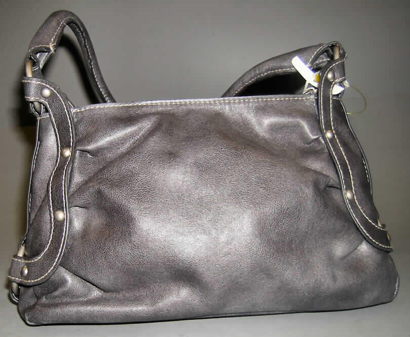 Handtasche, sog. Damenumhängetasche, siehe Foto,
- mit einer Außenseite aus Kunststofffolie (narbenartig geprägt) auf einer Spinnstoffunterlage,
- mit einem Hand- bzw. Schultertrageriemen,
- an den Schmalseiten mit aufgenieteten Zierriemen,
- mit einem Reißverschluss entlang dem oberen Rand,
- gefüttert, mit einem eingesetzten Reißverschlussfach und einem aufgenähten Handyfach,
- mit einer Größe von ca. 26 x 10 x 18 cm,
- Handtasche, da dazu bestimmt, kleinere persönliche Gegenstände aufzunehmen.