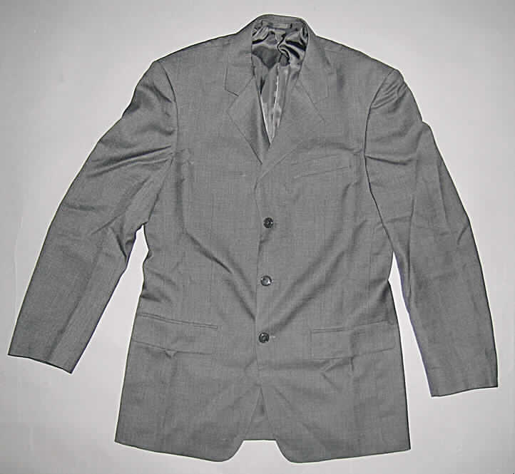 Jacke für Männer, sog. Sakko, in Erwachsenengröße, siehe Foto,
- aus 0,4 mm dicken, einfarbigen Geweben (dunkelgrau) aus laut Antrag 60% Wolle und 
  40% Polyester (synthetische Chemiefasern); durchgehend leicht gefüttert,
- über den Schritt reichend (Rückenlänge: 82 cm); mit Reverskragen,
- vorn durchgehend von links über rechts geknöpft (Männerkleidung),
- mit einer offenen, eingesetzten Brusttasche und zwei eingesetzten Taschen mit Patte 
  unterhalb der Taille,
- mit langen Ärmeln, an den Ärmelenden mit seitlicher Knöpfung; mit Schulterpolstern,
- in sechs Bahnen gearbeitet; mit einem ca. 24 hoch reichenden Rückenmittelschlitz,
- am unteren Rand durch Umschlagen und Festnähen gesäumt;
- wird üblicherweise nicht als äußerstes Kleidungsstück über jeder anderen Kleidung zum 
  Schutz gegen das Wetter getragen, somit kein Kleidungsstück der Position 6201.