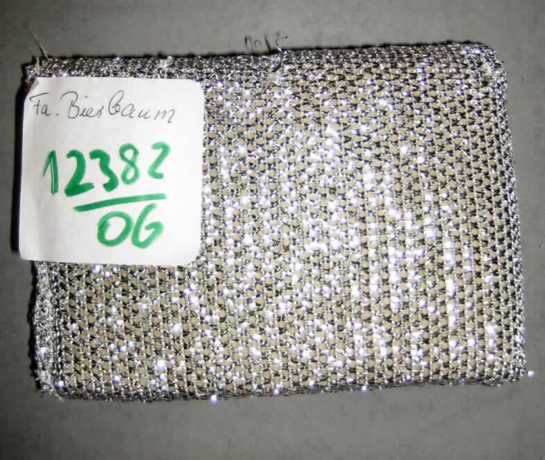 Reinigungsschwamm, sog. Lurex Reinigungsschwamm, siehe Foto,
- aus lt. Untersuchungsergebnis Gewirken aus metallisierten Streifen aus synthetischer 
  Spinnmasse (Breite der Streifen etwa 1 mm, somit Spinnstoff) und aus Garnen aus 
  synthetischen Chemiefasern,
- in der Art eines rechteckigen Schwamms,
- in den Abmessungen: etwa 13 x 9,5 x 1,5 cm,
- mit einem Kern aus zugeschnittenem Schaumkunststoff,
- durch Zusammennähen der Gewirke an den Seitenrändern konfektioniert,
- die Gewirke bestimmen insbesondere wegen ihrer Bedeutung in Bezug auf die Verwendung 
  der Ware als Reinigungsschwamm den Charakter der Ware (die rauhe Oberfläche des 
  Schwamms ermöglicht bei hartnäckigen Schmutzpartikeln den Reinigungseffekt; dies 
  wäre allein mit einem Schaumkunststoffschwamm nicht zu erreichen).
