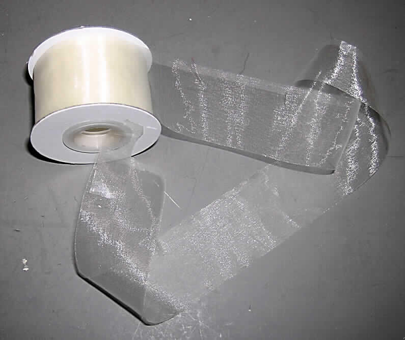 Band, sog. Chiffonband, Art. 77965, siehe Abbildung;,
- auf eine Spule aus Pappe (Aufmachung im Sinne der AV 5 b) aufgewickelt,
- als Meterware mit einer Länge, laut Antrag, von 20 m,
- laut Untersuchungsergebnis
-- mit einer Breite von ca. 3,8 cm,
-- mit unechten Webkanten an beiden Längsseiten (thermische Verfestigung),
-- aus 0,1 mm dicken Geweben aus laut Antrag 100% Polyester (synthetische Chemief.),
- einfarbig,
- kein Band aus Samt, Plüsch, Chenillegewebe oder Schlingengewebe, 
- keine Elastomergarne oder Kautschukfäden enthaltend,
- nicht konfektioniert, somit keine Ware der Position 6307.