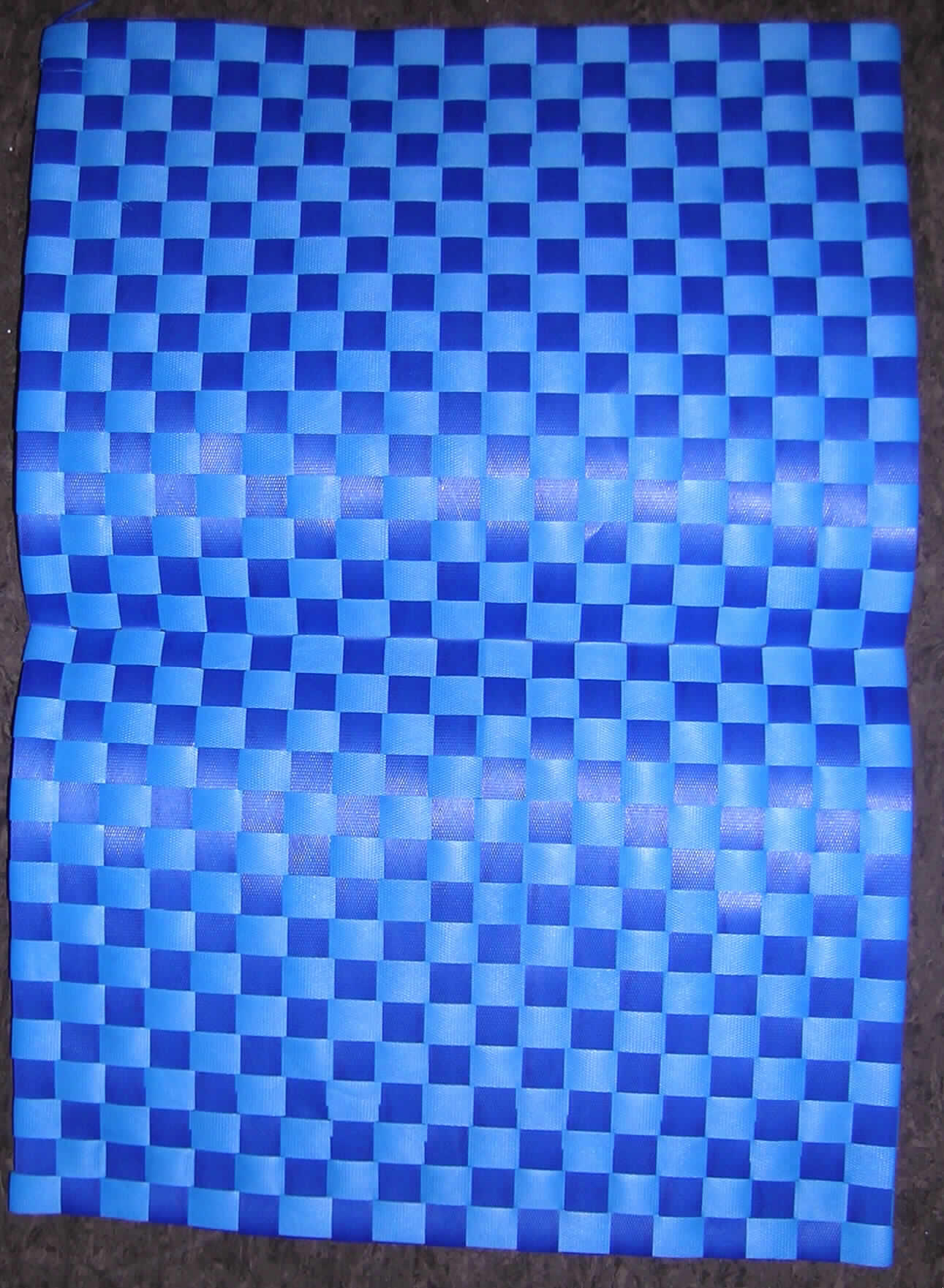 Tischplatzset,
- rechteckig (ca. 33,5 x 48 cm), 
- aus 16 mm breiten Streifen, aus Polypropylen lt. Angaben des Antragstellers (wegen der
  Streifenbreite von mehr als 5 mm handelt es sich um Flechtstoffstreifen), 
  die hergestellt sind aus parallel verlaufenden Spinnstofffasern, 
  die beidseitig mit Kunststoff überzogen und zusätzlich wabenförmig geprägt sind, 
  in Flächenform doppellagig verwebt.