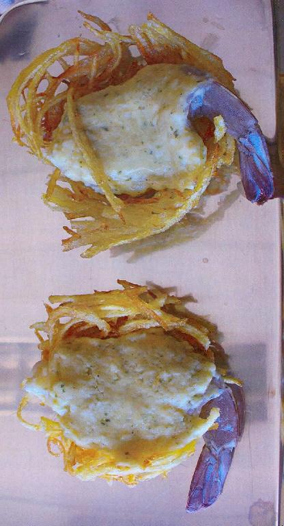 Nach den Angaben der Antragstellerin und der vorgelegten Warenprobe handelt es sich um eine gefrorene Lebensmittelzubereitung, die aus einem vorfrittierten Kartoffelkörbchen aus einzelnen Kartoffelstreifen besteht, in das eine rohe, teilgeschälte (sechstes Abdominalsegment sowie der Schwanzfächer sind noch vorhanden) Garnele der Art Penaeus vannamei eingelegt wurde. Die Garnele ist bis auf den Restpanzer mit einem Parmesantopping bedeckt. Der Anteil der Garnele an der Zubereitung beträgt dabei über 40 Prozent.

Insgesamt 6 solcher Lebensmittelzuberbereitungs sind auf einem Kunststofftablett luftdicht mit Kunststofffolie umschweißt und in einem Verkaufskarton (Gesamtinhalt 200 g) für den Einzelverkauf aufgemacht.