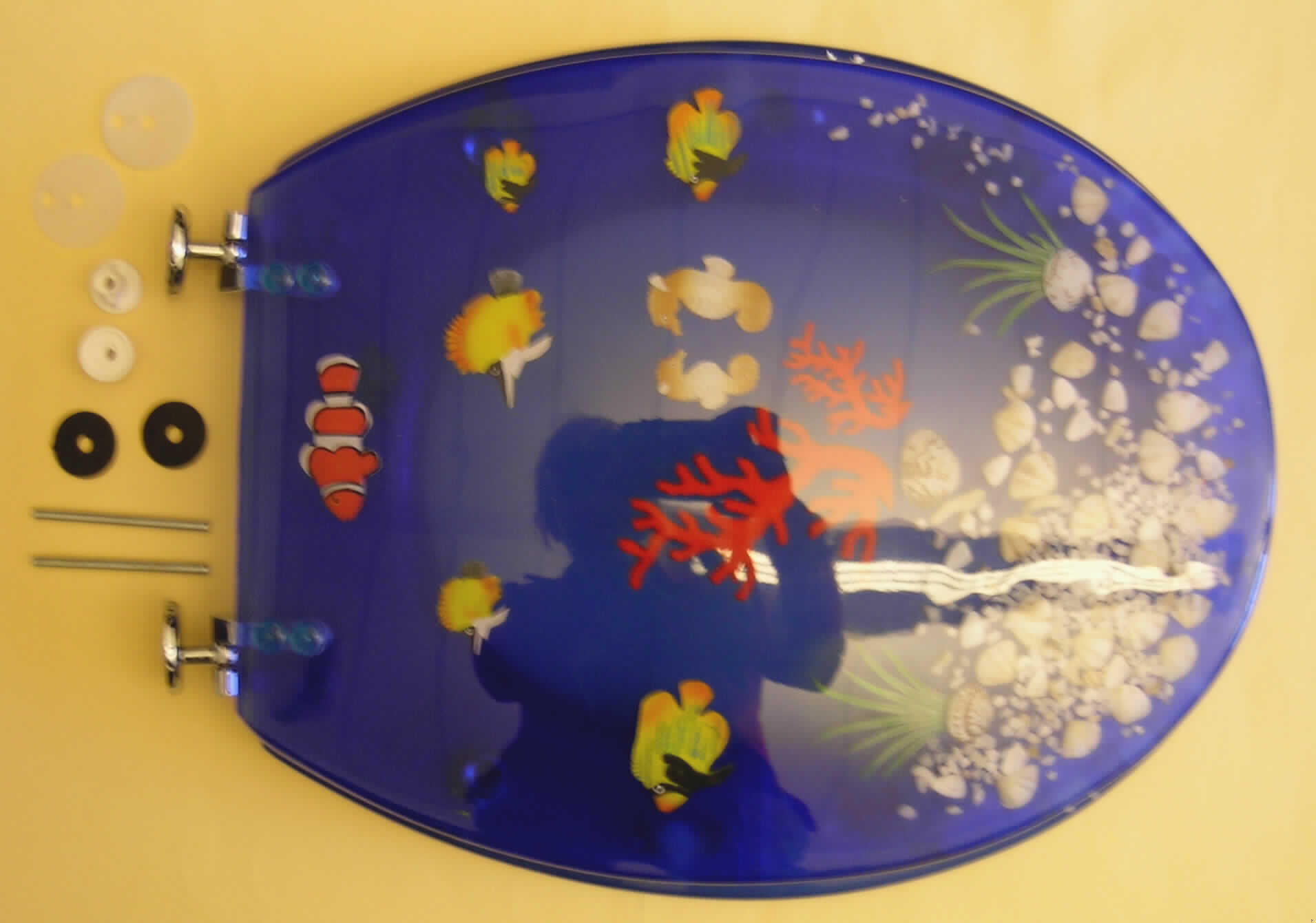 Toilettensitz mit Deckel aus einem blau gefärbten, durchsichtigen Kunststoff im Sinne der Anmerkung 1 zu  Kap. 39 (charakterverleihend) mit eingelassener, stilisierter Unterwasserlandschaft (Muscheln, Steine, Fische, Pflanzen). Die Verbindungs- und Befestigungsscharniere bestehen aus unedlem Metall.
Die Ware ist in einem Pappkarton mit Foliensichtfenster für den Einzelverkauf aufgemacht.