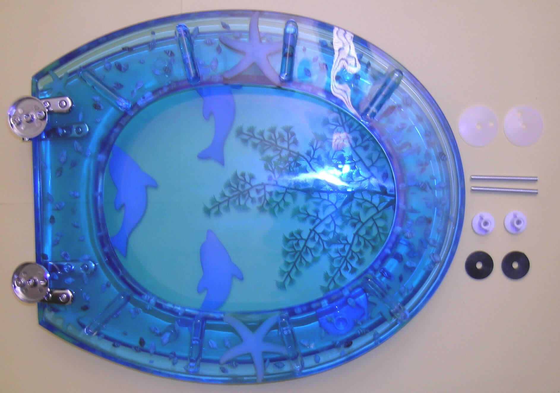 Warenzusammenstellung in Aufmachung für den Einzelverkauf (Pappumschließung), bestehend aus:
- einem Toilettensitz mit Deckel aus einem blau gefärbten, transparenten Kunststoff im Sinne 
  der Anmerkung 1 zu  Kapitel 39 (charakterverleihend) mit eingelassener, stilisierter 
  Unterwasserlandschaft, i. W. in Form von Delphinen, Muscheln und Seesternen sowie
  Verbindungsscharnieren aus unedlem Metall und
- Montagematerial zur Befestigung des Sitzes auf dem Toilettenbecken, bestehend aus 
  zwei Schrauben aus unedlem Metall, zwei Abstandhaltern aus Kunststoff und
  vier Trennscheiben.
Charakterverleihend nach Verwendungszweck und Umfang ist der Toilettensitz.