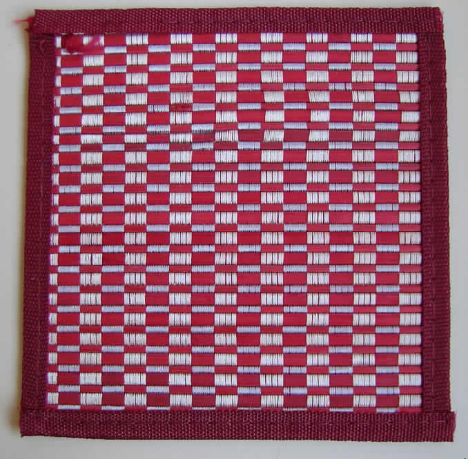 Matte (sog. Untersetzer) 
- quadratisch, in den Abmessungen von ca. 18 x 18 cm,
- aus pflanzlichen Flechtstoffen hergestellt (aus parallel aneinandergefügten Streifen aus
  Bambus (Breite ca. 5 mm), die nebeneinander gelegt und durch Haltefäden aus Spinnstoff- 
  garnen in unterschiedlichen Farben dekorativ in der Art eines Karomusters in Flächenform 
  verbunden sind),
- mit einer ca. 1,2 cm breiten Randeinfassung aus Spinnstoffgewebe,
- auf der Rückseite mit einem undichten Spinnstoffgewebe zur Verstärkung unterlegt.
Die pflanzlichen Flechtstoffe verleihen der Ware insbesondere nach Umfang und im Hinblick auf die Verwendung als Untersetzer ihren Charakter.