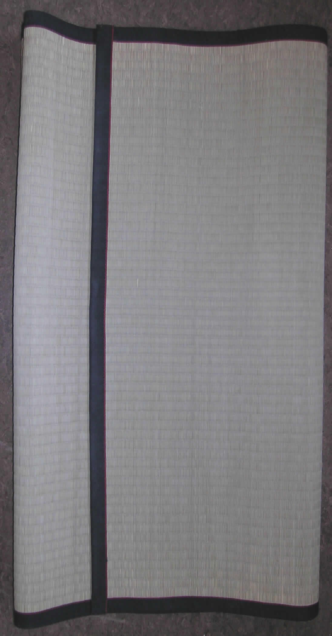 Matte (sog. Tatami-Matte (Goza)) 
- rechteckig, in den Abmessungen von ca. 90 x 200 cm,
- charakterverleihend hergestellt aus pflanzlichen Flechtstoffen (aus parallel aneinander- 
  gefügten Halmen aus -lt. Angaben des Antragstellers- Gras, die nebeneinander gelegt 
  und durch Haltefäden aus Spinnstoff in Flächenform verbunden sind).
- an den Rändern mit einem ca. 2,5 cm breiten Gewebestreifen eingefasst.