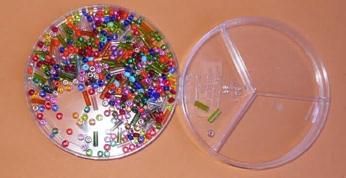 Bei der als "Hairclip bijou" bezeichneten Ware handelt es sich um ein Set zum Basteln von Haarschmuck, bestehend aus verschiedenen Bastelutensilien  unterschiedlicher Materialbeschaffenheit in Form von Haarspangen, Glas- und Kunststoffperlen, Pailletten, künstlichen Blüten, versilbertem Kupferdraht, einer Tube Klebstoff und einer Bastelanleitung, die gemeinsam in einem Pappkarton für den Einzelverkauf aufgemacht sind. Da die Bastelutensilien nicht in einer genau vorgegebenen Menge und Form vorliegen, kommt eine Einreihung als Warenzusammenstellung im Sinne der AV 3 b) nicht in Betracht. Die Waren sind somit voneinander getrennt einzureihen.

Glasperlen
- kleine, runde, bunte, durchbohrte Glasperlen mit unterschiedlichen Durchmessern
  (ca. 1,5, 2, 2,5 und 3 mm) und unterschiedlichen Längen (ca. 1,5, 2,0, 2,5 und 7 mm)
- hergestellt aus Glasröhrchen, teilweise in der Masse gefärbt,
- nicht geschliffen und mechanisch poliert,
- zum Herstellen von Hairclips bestimmt,
- augenscheinlich nicht handgearbeitet,
- verpackt in einer unterteilten Kunststoffdose.