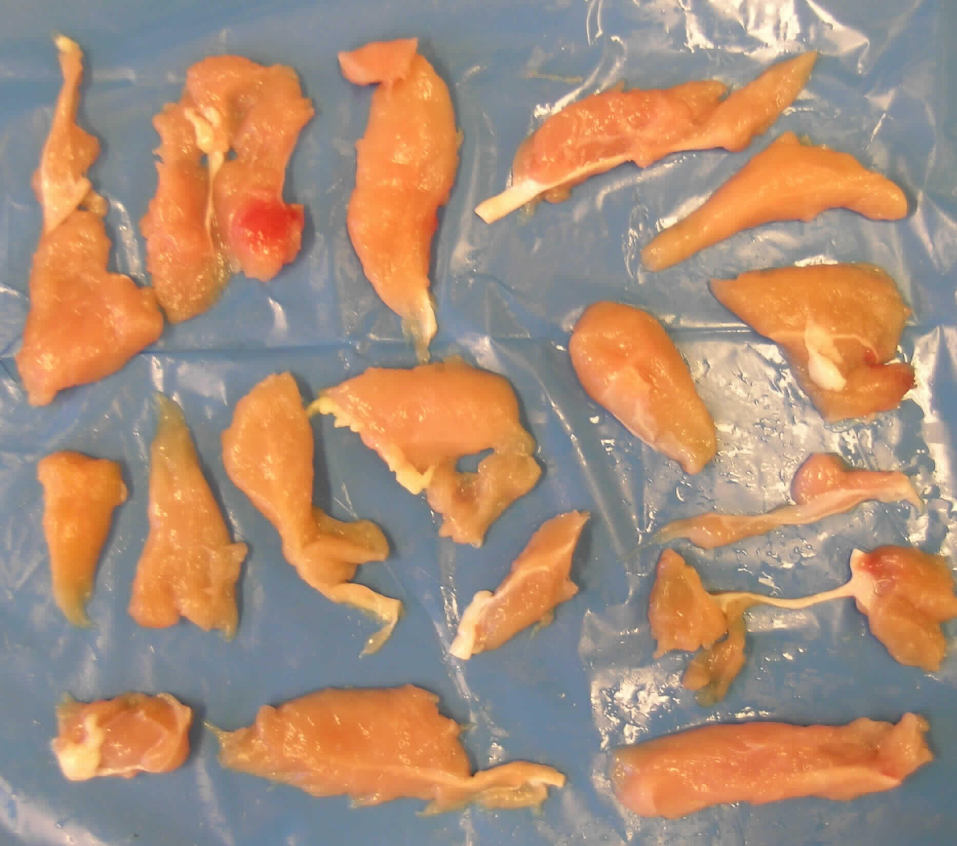 Nach den Antragsangaben und der vorgelegten Warenprobe handelt es sich um rohes, entbeintes Fleisch vom Hausgeflügel (Hühner). Die kleinen, unregelmäßig geformten Fleischstücke fallen beim Zuschneiden von Hühnerbrüsten an. Sie sind teilweise mit gewachsenen Sehnen oder gewachsenem Fett durchsetzt oder mit Blut behaftet. Die Stücke wurden zu einem Block mit einem Nettogewicht von 7,5 kg gefroren und anschließend in Kunststofffolie verpackt.