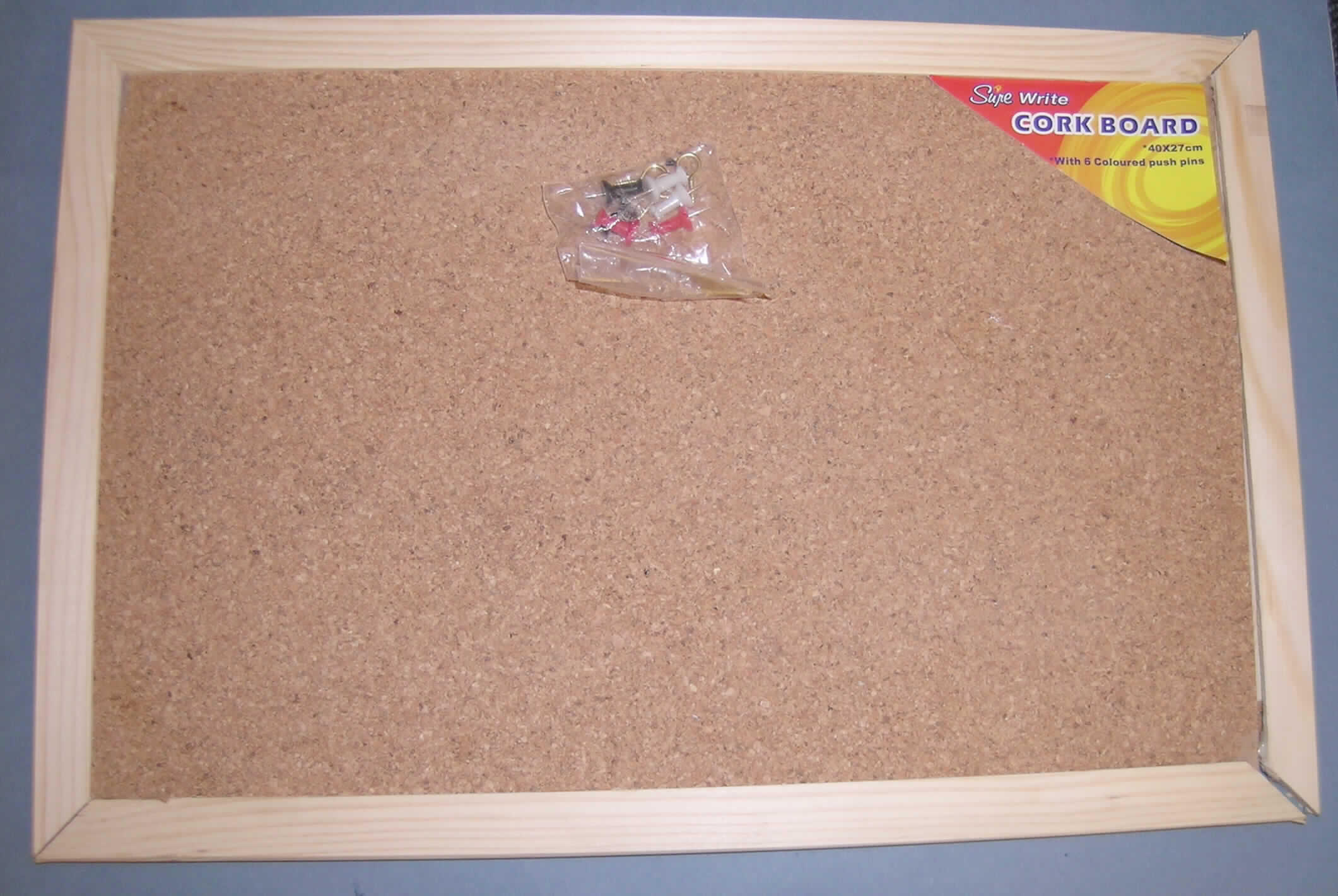 Ware aus Presskork in Form einer ca. 40 x 27 cm großen Pinnwand bestehend aus: 
- einem Rahmen aus Holzprofilen,
- einer in den Rahmen eingeklebten zweilagigen Platte mit einer Vorderseite aus Presskork  (Dicke ca.  0,8 mm)   und einer Rückseite aus Wellpappe (Dicke ca. 4,2 mm), die  miteinander verklebt sind,
- mit drei Aufhängeösen aus unedlem Metall ausgestattet, die in den Rahmen eingeschraubt werden können und 
- mit sechs beigefügten Pinnadeln versehen.
Die Korklage ermöglicht ein mehrfaches Einstecken und Halten der Nadeln ohne Beschädigung der Pinnwand und ist daher nicht nur hinsichtlich des Umfangs, sondern  insbesondere im Hinblick auf die dauerhafte Verwendung charakterverleihend.
