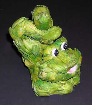 "Frosch Handstand",
- stilisierte Froschnachbildung, mit Korpus aus Schaumkunststoff ohne eigene Zierwirkung, 
  vollständig mit grün gefärbten, getrockneten Artischockenblütenblättern beklebt 
  (Höhe ca. 13,5 cm), 
- mit Augen aus Kunststoff und Mund aus Papier,
- wird üblicherweise auch vom Blumenhandel zu Dekorations- oder Zierzwecken angeboten.
(Abbildung siehe Anlage)
Der Charakter des Ganzen wird durch die getrockneten, gefärbten Blütenblätter bestimmt.

"Ziergegenstand aus getrockneten und gefärbten Blütenblättern, weitergehend bearbeitet als nur getrocknet und gefärbt, nicht zur Herstellung von Potpourries (zusammengesetzte Ware aus getrockneten Blütenblättern -charakterbestimmend- und Kunststoff); sog. Frosch Handstand"