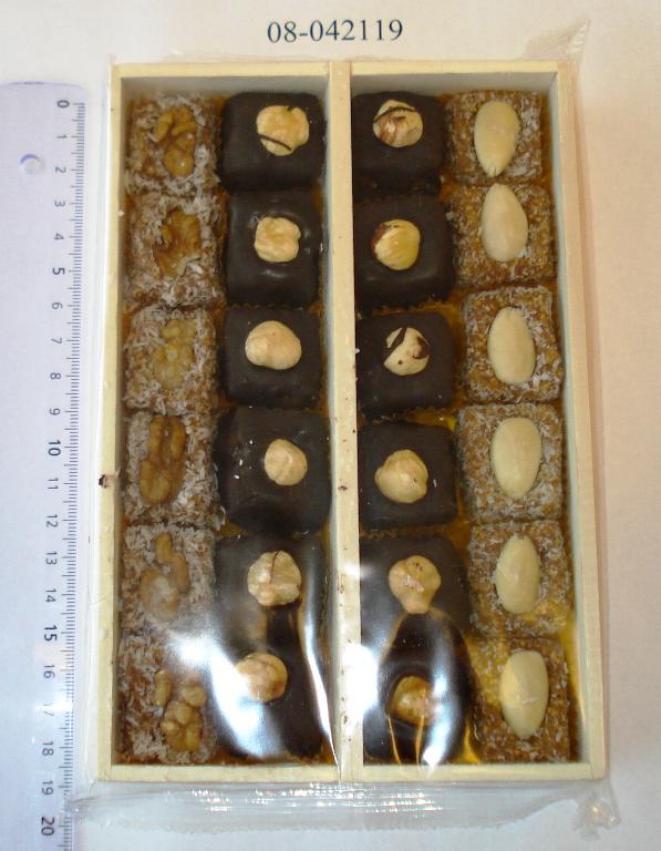 Produktet foreligger som stykker af figenpasta i detailsagsemballage.

Produktet er en blanding af stykker af figenpasta, bestående af

•	Ca 200 g hakkede, tørrede figner, hvor hvert stykke er overtrukket med chokolade og pyntet med 1 hasselnød
•	Ca 84 g hakkede, tørrede figner, hvor hvert stykke er vendt i kokos og pyntet med 1 mandel
•	Ca 88 g hakkede, tørrede figner, hvor hvert stykke er vendt i kokos og pyntet med 1 valnød. 

Stykkerne er i detailsalgsemballage, som er en trææske med 1 skillerum. I det ene rum er der en række figenpasta stykker, rullet i kokos og pyntet med valnød og en række figenpasta stykker overtrukket med chokolade og pyntet med en hasselnød. I det andet rum er der en række figenpasta stykker, rullet i kokos og pyntet med valnød og en række figenpasta stykker overtrukket med chokolade og pyntet med en hasselnød. Æsken er emballeret med klar folie. Trææskens mål er 12,4 cm x 18,8 cm x 3,0 cm.